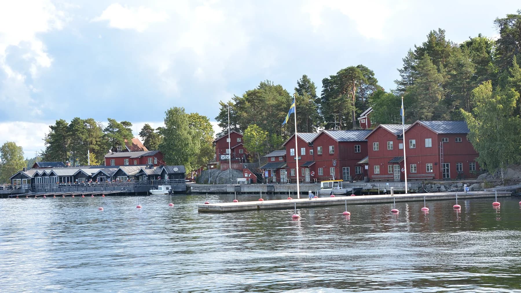 Röda hus och bryggor vid vattnet på Fjäderholmarna