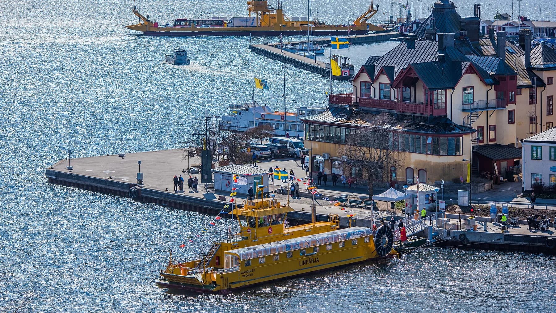 Vaxholms livliga hamn med kajer, båtar och färgstarka trähus