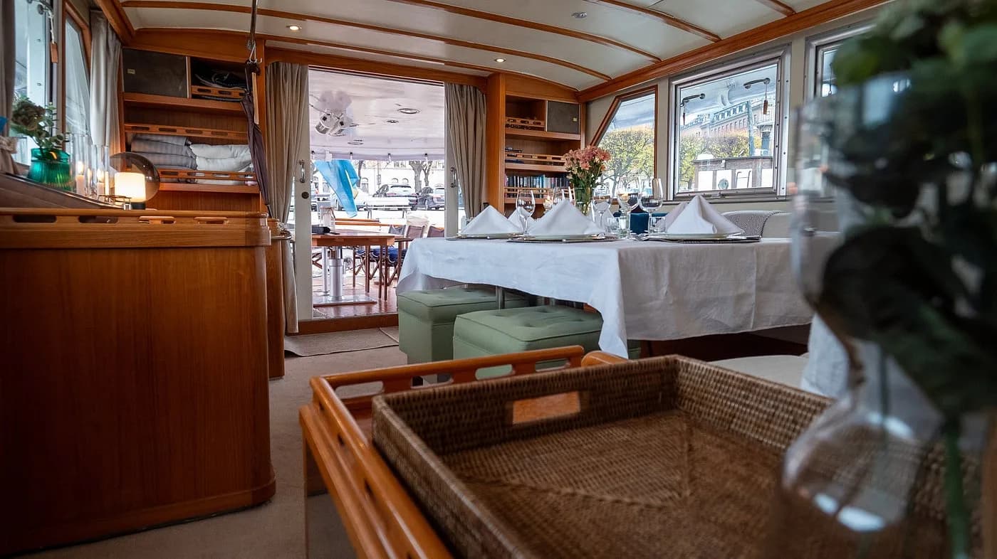 Salongen ombord M/Y Gaia med dukat bord och vy ut mot Strandvägen